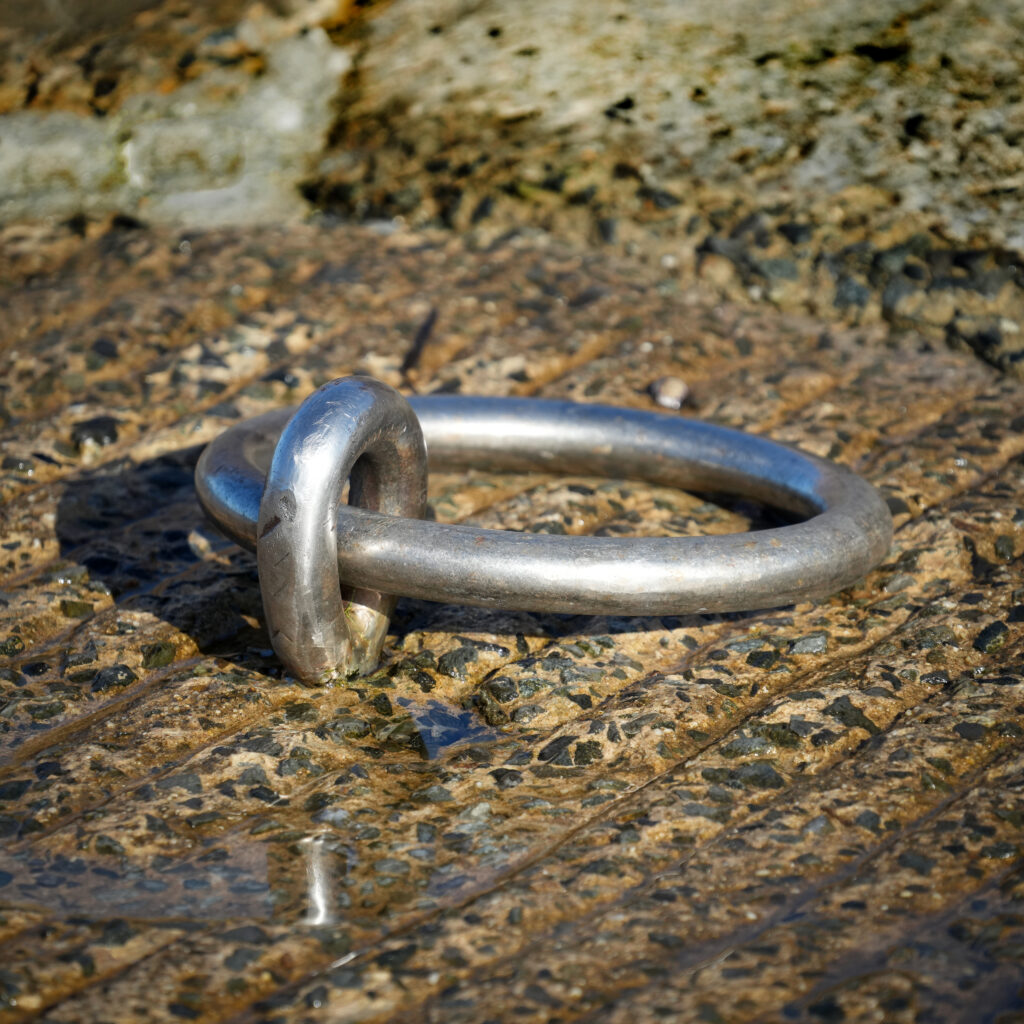 Maillon métallique argenté posé sur une pierre mouillée - symbole de connexion et de lien